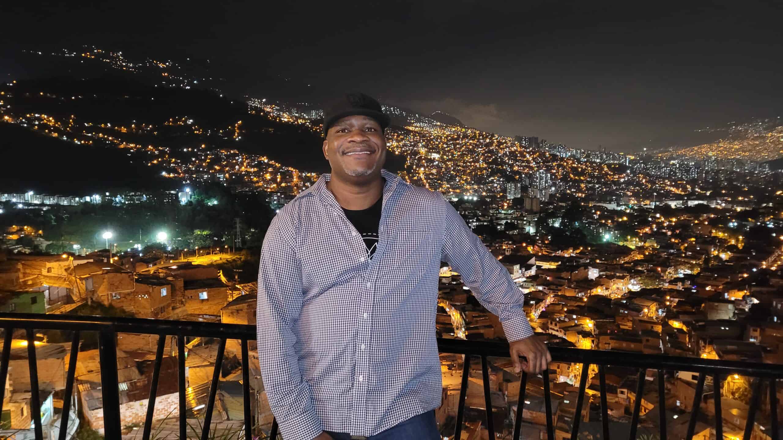 Shep of GeoGringo at a Comuna 13 lookout point with the Medellin skyline behind him, Colombia