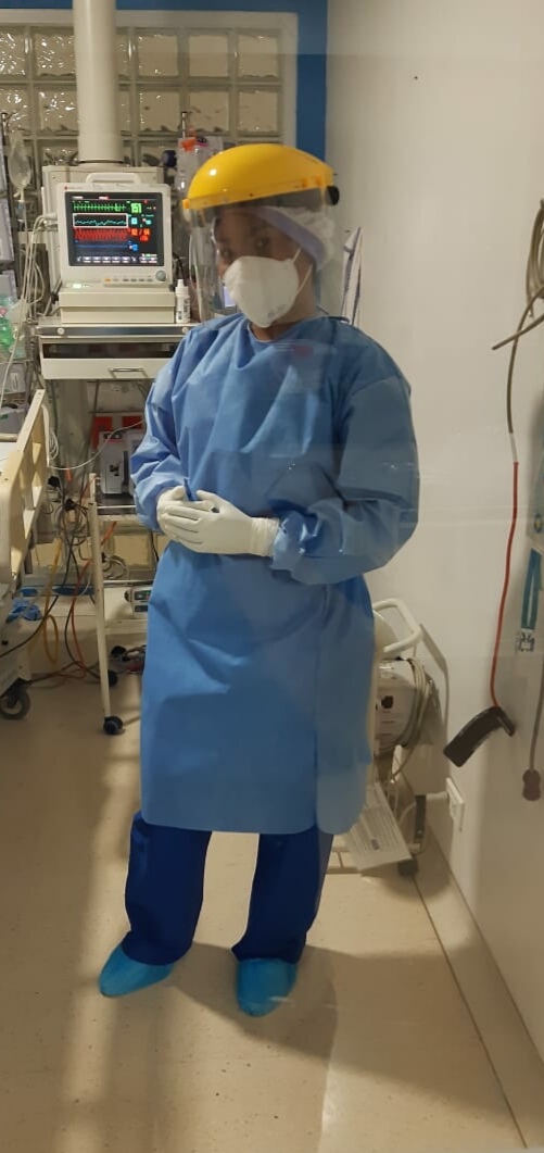 A nurse in full personal protective equipment in a Colombian clinic treatment room