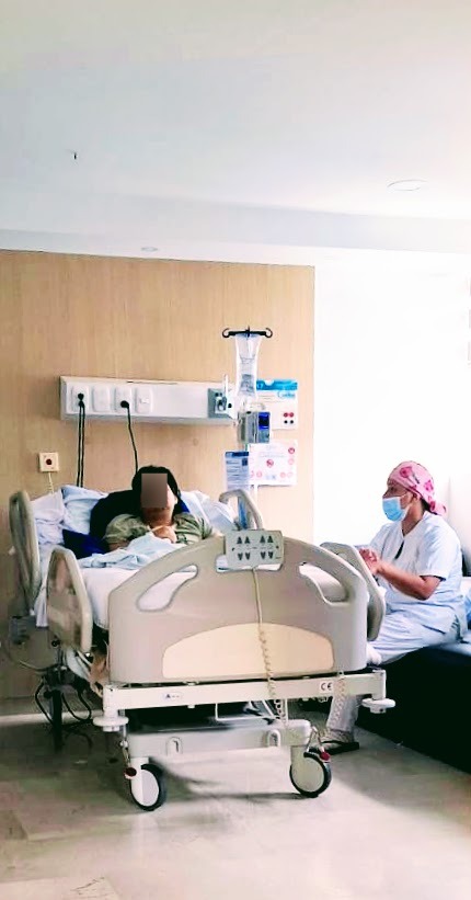 A patient and a nurse in a private hospital room in Colombia